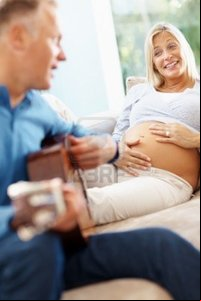 wife mature logos mature man plays guitar his pregnant wife home photo